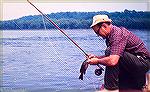 Inky Moore of Carlisle, Pennsylvania with a smallmouth bass caught on the Susquehanna River just north of Three Mile Island. Image circa 1974.